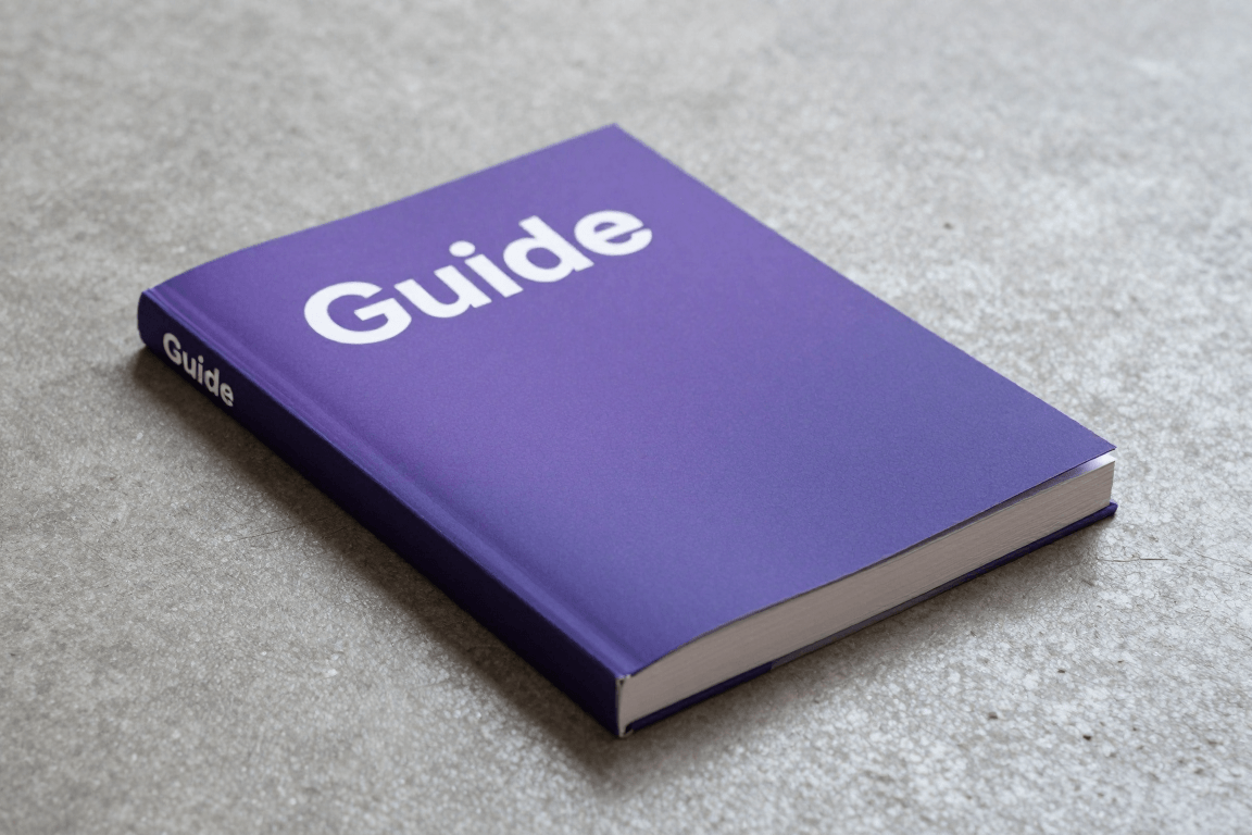 En bokhylla med referensböcker och några små föremål på ett träbord i sent kvällsljus från en lampa